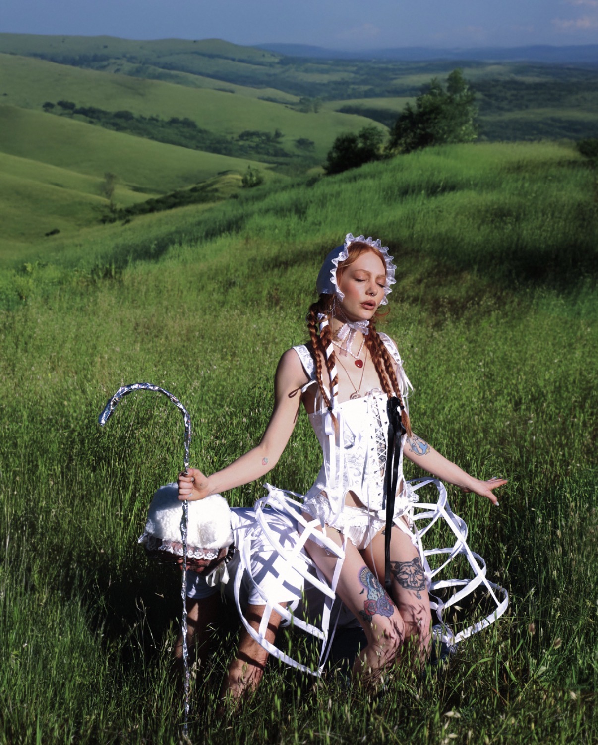 Mistress Luna in full-length white shepherdess styling against rolling hills