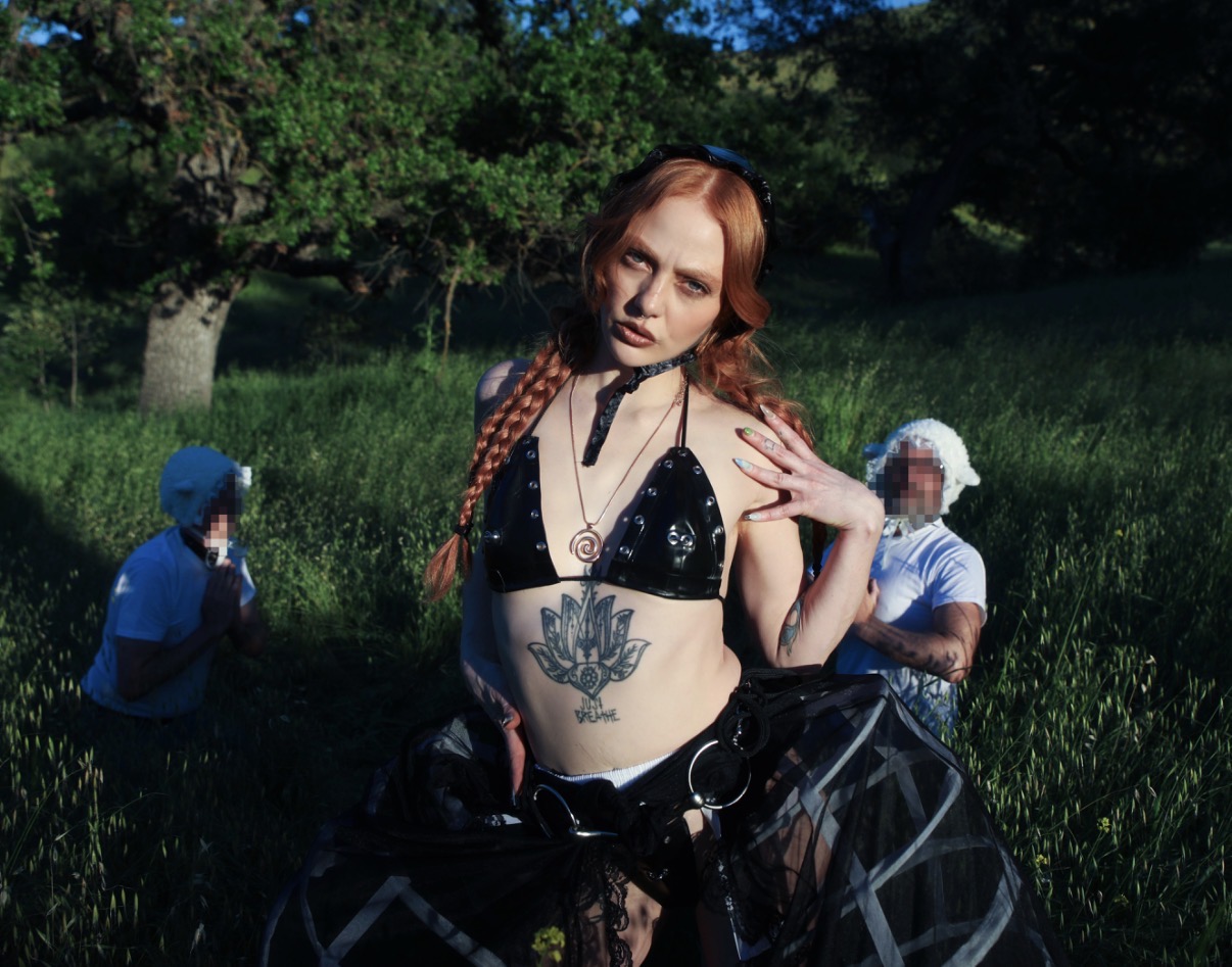 Mistress Luna in black shepherdess styling holding a direct gaze with submissive sheep figures