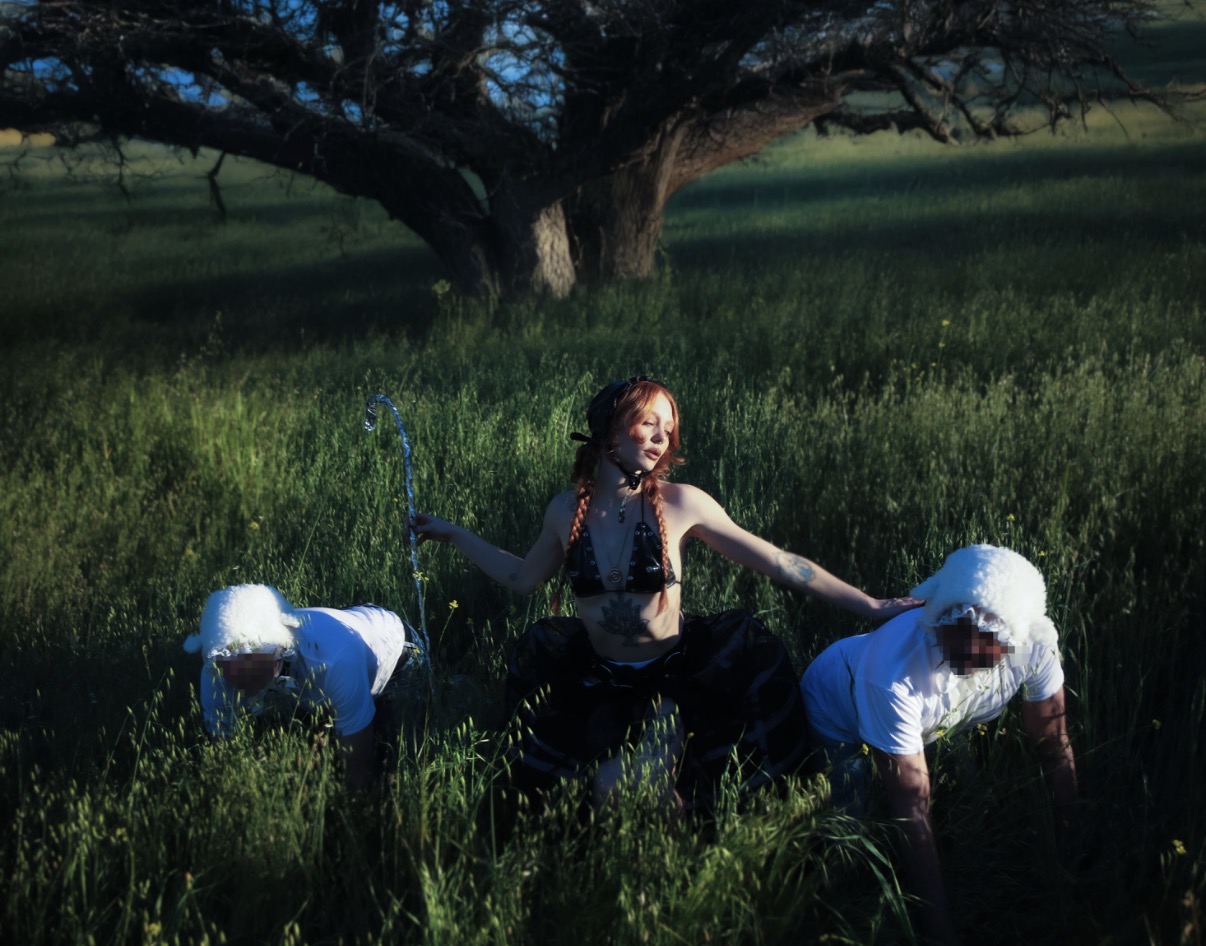 Mistress Luna in dark shepherdess styling with a crook and submissive sheep figures